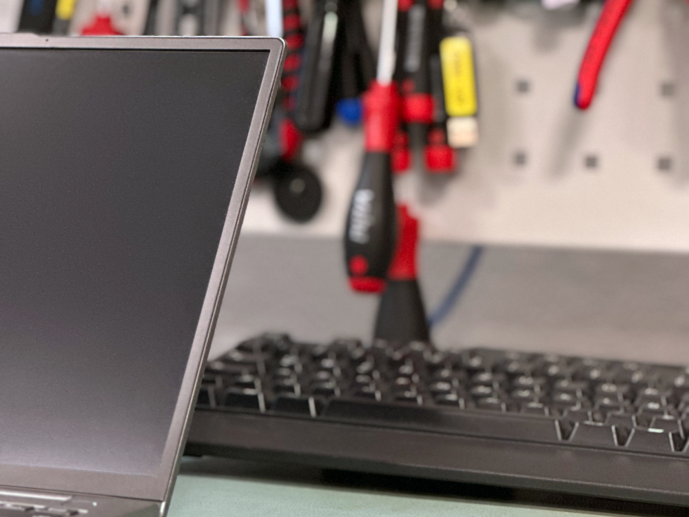 Man sieht leicht verschwommen den Arbeitsplatz eines Technik Mitarbeiters. im Vordergrund stehen eine Tastatur und ein Notebook.